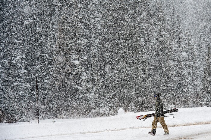 (Chris Detrick | The Salt Lake Tribune) A skier walks along South Brighton Loop Road in Brighton Saturday, December 23, 2017.