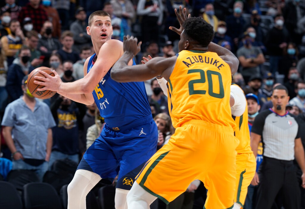 Denver Nuggets center Nikola Jokic, left, looks to pass the ball as Utah Jazz center Udoka Azubuike defends during the first half of an NBA basketball game Wednesday, Jan. 5, 2022, in Denver. (AP Photo/David Zalubowski)