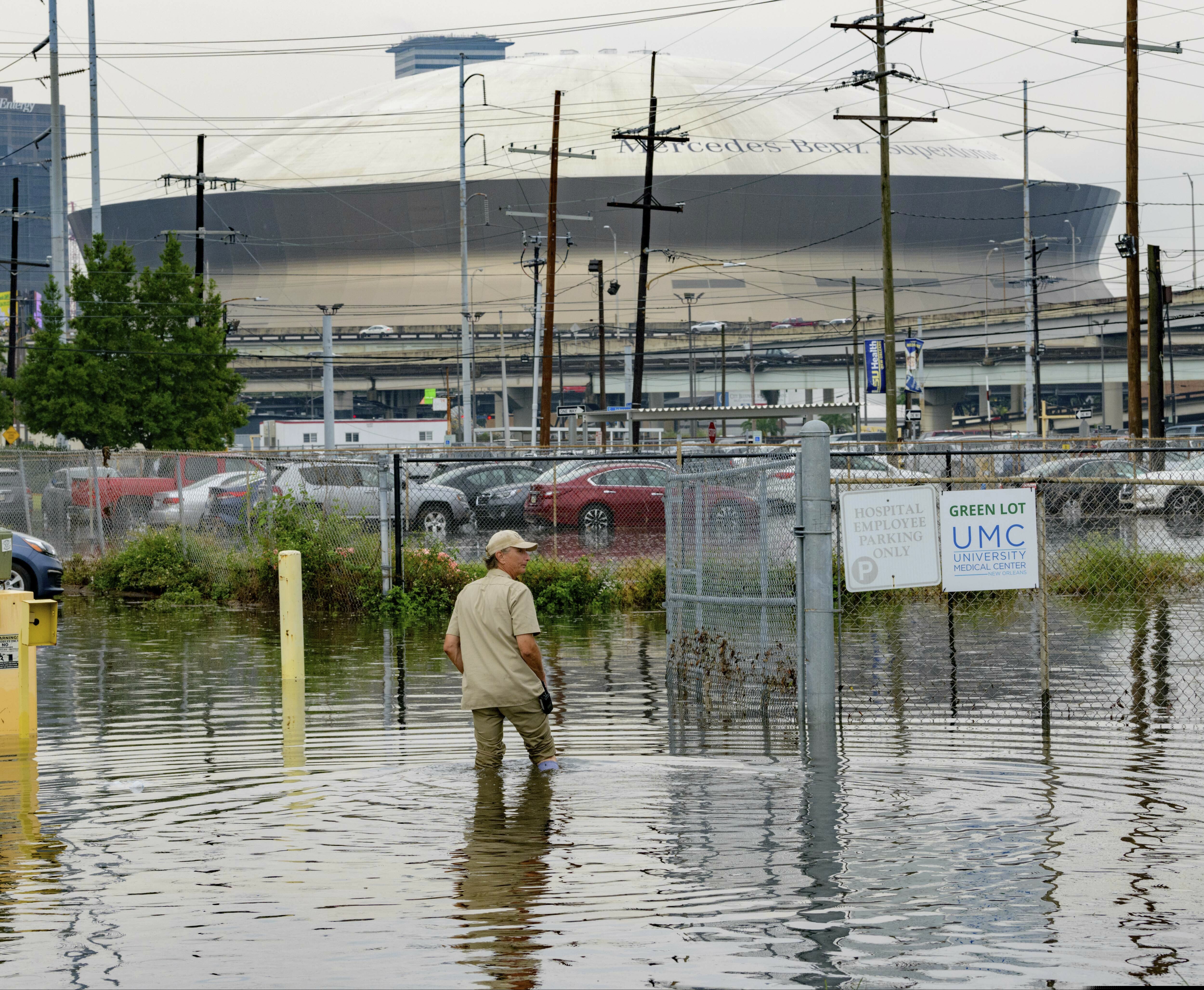 (Matthew Hinton | AP Photo) Frank Conforto Jr. walks in the parking lot of the University Medical Center (UMC) with the Mercedes-Benz Superdome in the background on Glavez Street in New Orleans after flooding from a storm Wednesday, July 10, 2019. Louisiana Gov. John Bel Edwards has declared a state of emergency in anticipation of tropical weather that could dump as much as 15 inches (38 centimeters) of rain in the state over the coming days.