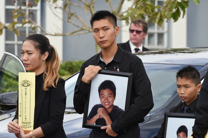 Jason Wang, center, holds a picture of his brother Peter, along with his younger brother, Alex, after his brother's funeral at Kraeer Funeral Home in Coral Springs, Fla., Peter Wang is a victim in the shooting at Marjory Stoneman Douglas High School.  (Taimy Alvarez/South Florida Sun-Sentinel via AP)