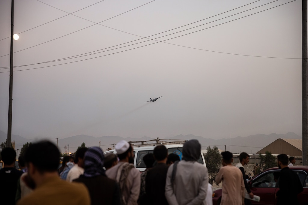(Jim Huylebroek | The New York Times) Hoping to flee the country, people gather outside the airport in Kabul, Afghanistan on Friday, Aug. 20, 2021, as a military cargo plane takes off. Since sweeping into Kabul last weekend, the Taliban have moved swiftly to cement their control over Afghanistan, dispersing protests with force and hunting down opponents despite pledges of amnesty, according to witnesses and a security assessment prepared for the United Nations.