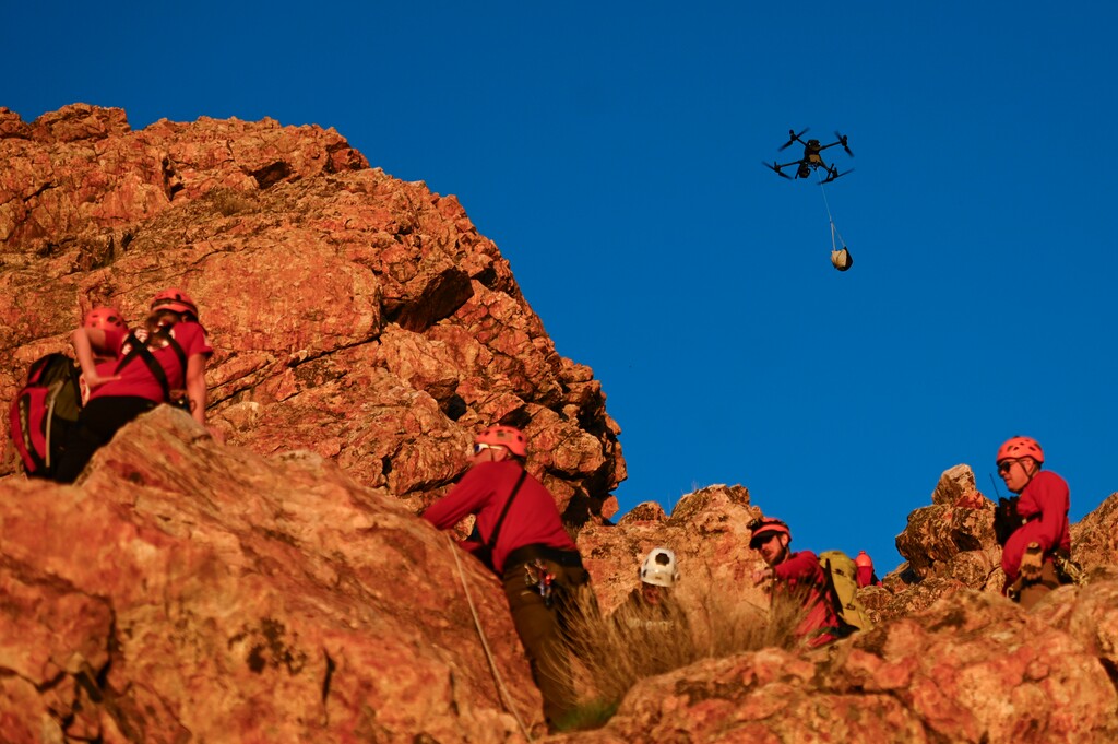 (Alex Goodlett | The New York Times) A DJI drone flies supplies to a Weber County Search and Rescue training exercise in Ogden, Utah, on April 11, 2024. U.S. authorities consider Chinese drone maker DJI a security threat; Congress is weighing legislation to ban it, prompting a lobbying campaign from the company, which dominates the commercial and consumer drone markets.