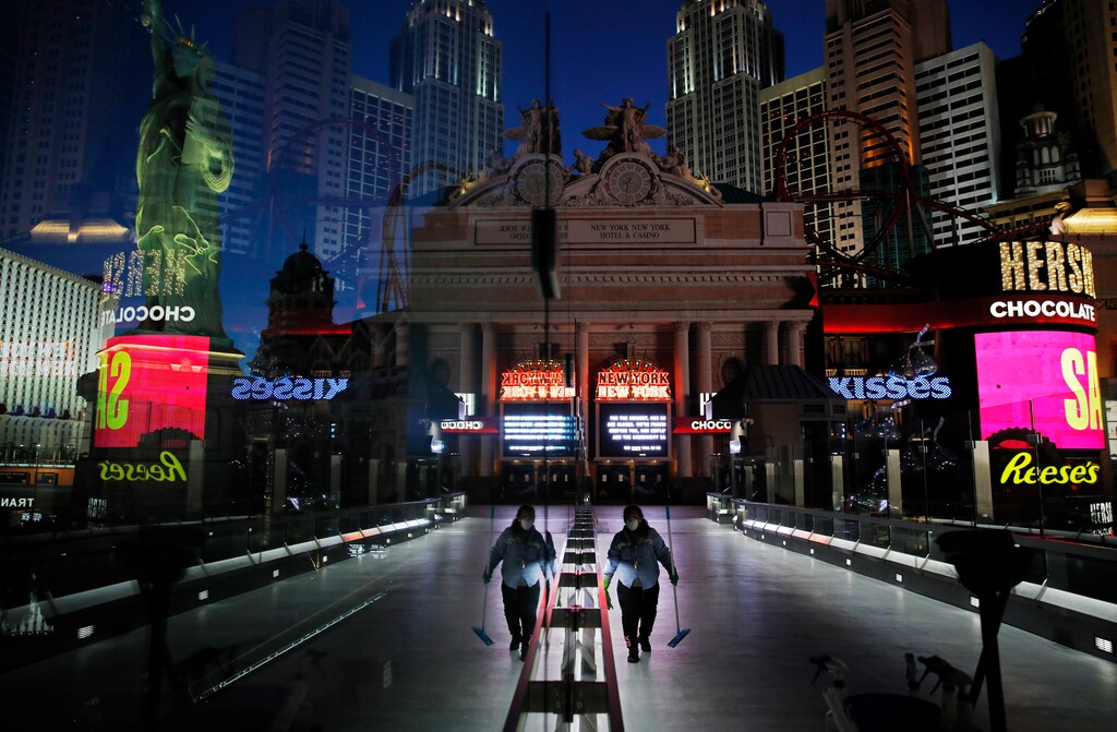 (John Locher | AP file photo) On April 18, a lone worker wearing a mask cleans a pedestrian walkway devoid of the usual crowds as casinos and other business are shuttered due to the coronavirus outbreak in Las Vegas. Nevada's governor closed the glitzy casinos and nightlife attractions in mid-March, leaving much of the famous gambling mecca empty, barricaded and abandoned.