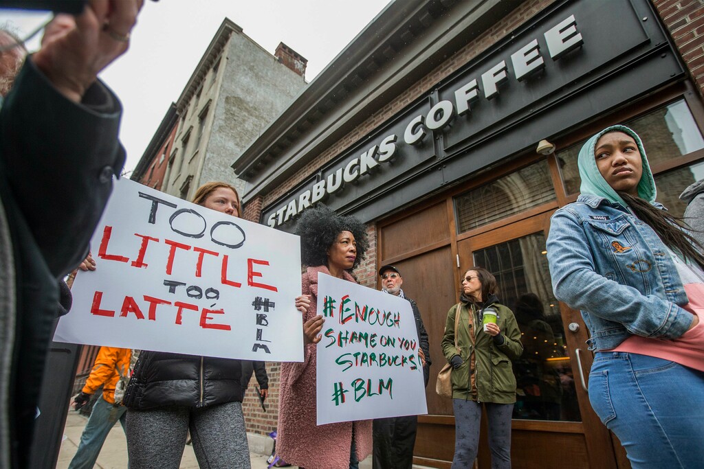 Protesters gather outside of a  Starbucks in Philadelphia, Sunday, April 15, 2018, where two black men were arrested Thursday after employees called police to say the men were trespassing. The arrest prompted accusations of racism on social media. Starbucks CEO Kevin Johnson posted a lengthy statement Saturday night, calling the situation "disheartening" and that it led to a "reprehensible" outcome.  (Michael Bryant/The Philadelphia Inquirer via AP)