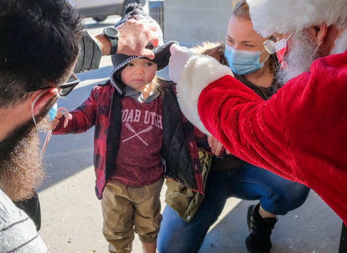 (Leah Hogsten  |  The Salt Lake Tribune)  Hansen Albert, 2, gets a better look at Santa on Christmas Eve as Jace Karson and Bella Blake watch his reaction at Macey's grocery store on Thursday. The jolly fat man also greeted Macey's guests who scheduled a grocery pickup time, Dec. 24, 2020.
