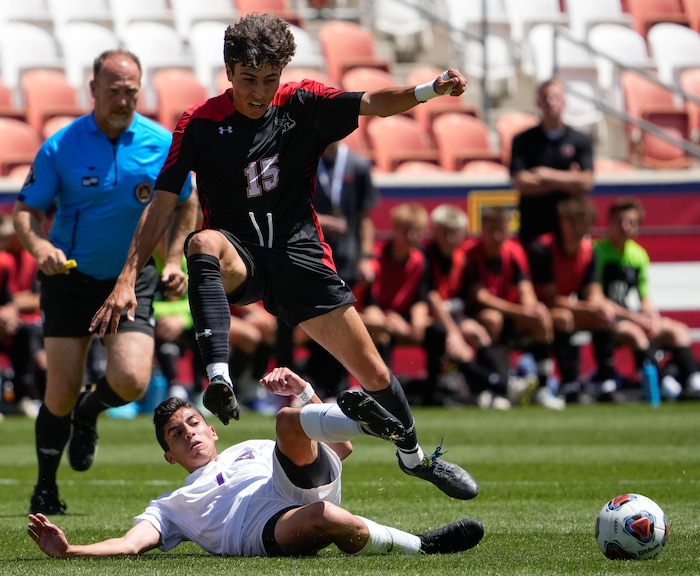 (Francisco Kjolseth | The Salt Lake Tribune) Alta’s Peter Affleck (17) steps over Lehi’s Benny Forbes (7) during their 5A State Soccer Championship title game at Rio Tinto Stadium, Wednesday, May 25, 2022. Alta defeated Lehi in shootout 3-1.