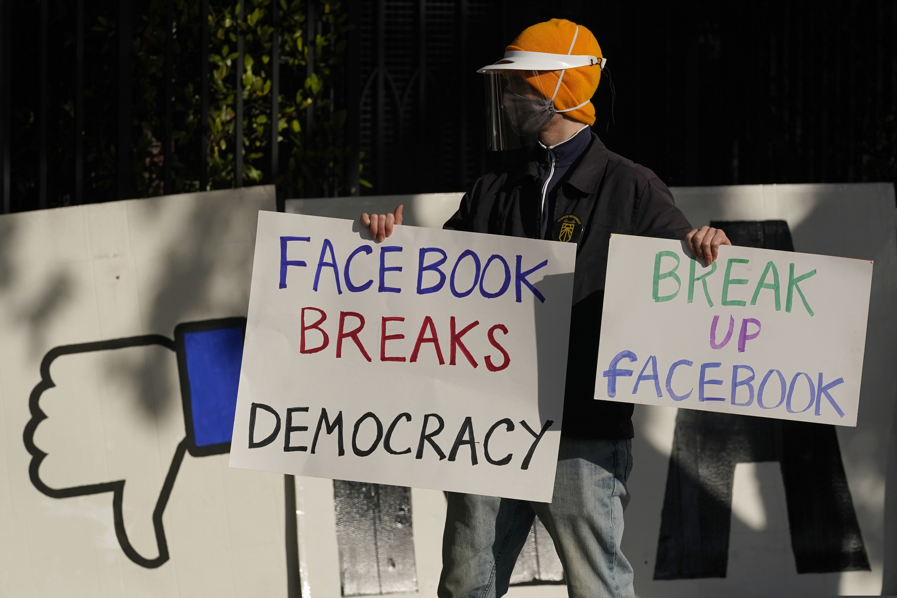 (Jeff Chiu | AP photo) In this Nov. 21 photo, a demonstrator joins others outside of the home of Facebook CEO Mark Zuckerberg to protest what they say is Facebook spreading disinformation in San Francisco. Federal regulators asked Wednesday, Dec. 9, 2020, for Facebook to be ordered to divest its Instagram and WhatsApp messaging services as the U.S. government and 48 states and districts accused the company of abusing its market power in social networking to crush smaller competitors. The antitrust lawsuits were announced by the Federal Trade Commission and New York Attorney General Letitia James.