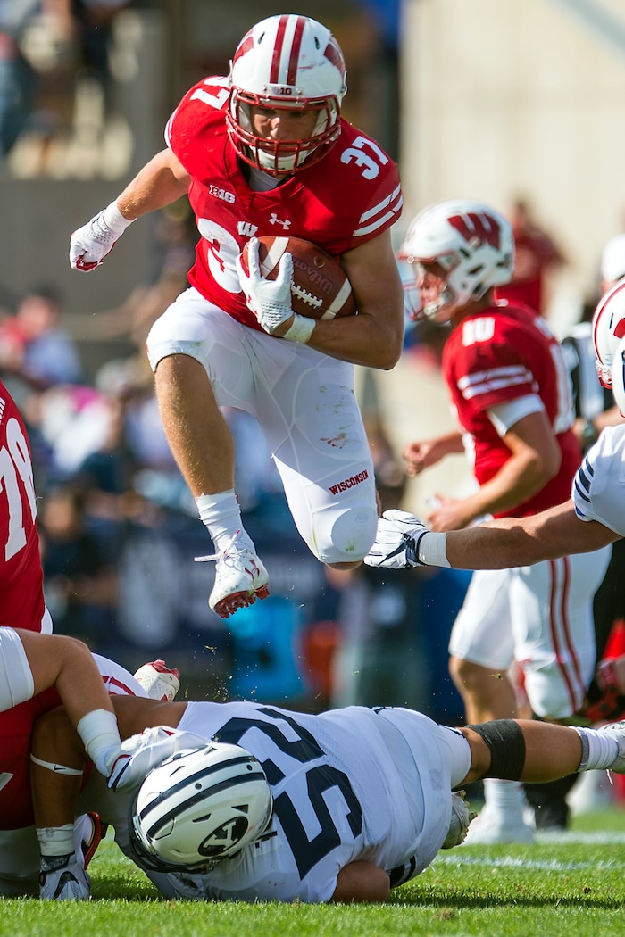 (Chris Detrick  |  The Salt Lake Tribune)   Wisconsin Badgers running back Garrett Groshek (37) leaps over Brigham Young Cougars defensive lineman Trajan Pili (52) during the game at LaVell Edwards Stadium Saturday Saturday, September 16, 2017. Wisconsin Badgers defeated Brigham Young Cougars 40-6.