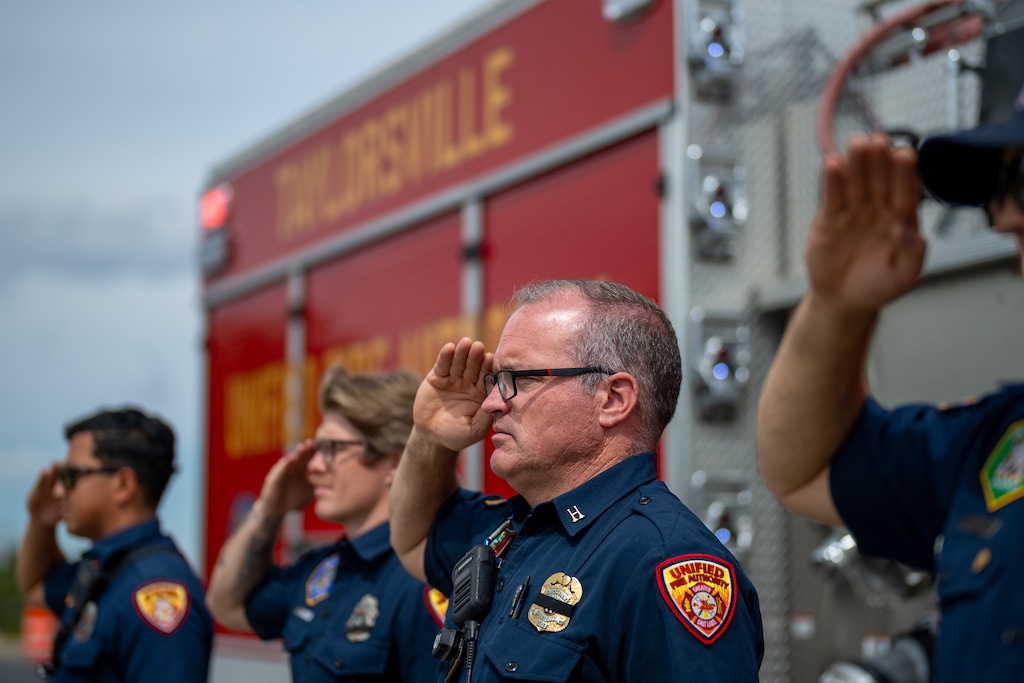 (Trent Nelson  |  The Salt Lake Tribune) Unified Fire Authority Capt. Brian Christensen salutes as the procession for two pilots killed battling the massive Widemouth 2 Fire passes through Taylorsville on Friday, Aug. 14, 2026.