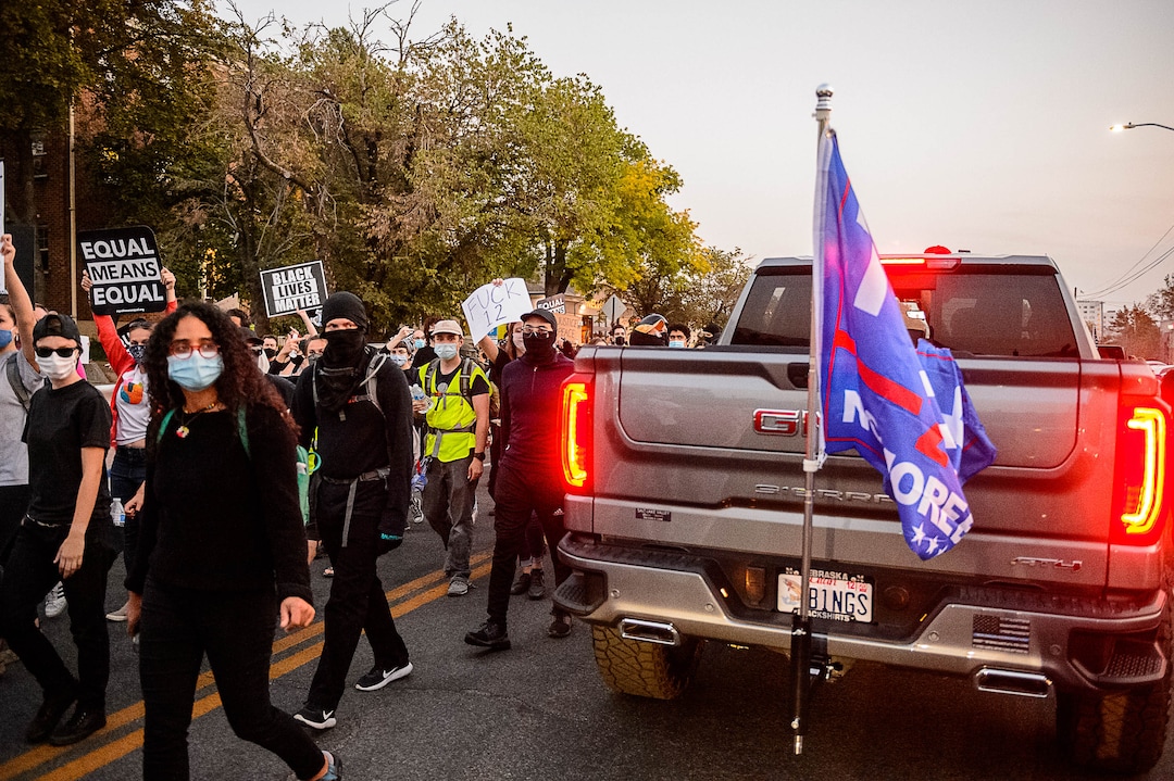 (Trent Nelson  |  The Salt Lake Tribune) Protesters march past a truck with a Trump flag as Vice President Mike Pence and Sen. Kamala Harris prepare to debate at Kingsbury Hall in Salt Lake City on Wednesday, Oct. 7, 2020.