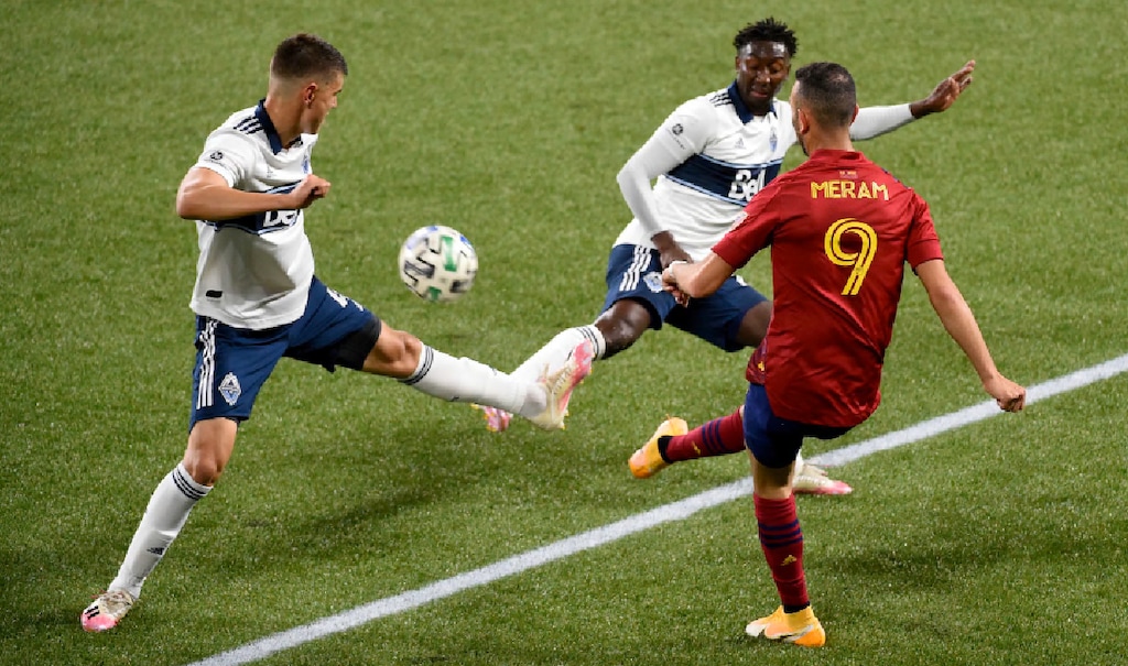 Real Salt Lake forward Justin Meram, right, passes the ball between Vancouver Whitecaps defender Ranko Veselinovic, left and midfielder Janio Bikeli, center, during the first half of an MLS soccer match in Portland, Ore., Saturday, Oct. 10, 2020. (AP Photo/Steve Dykes)