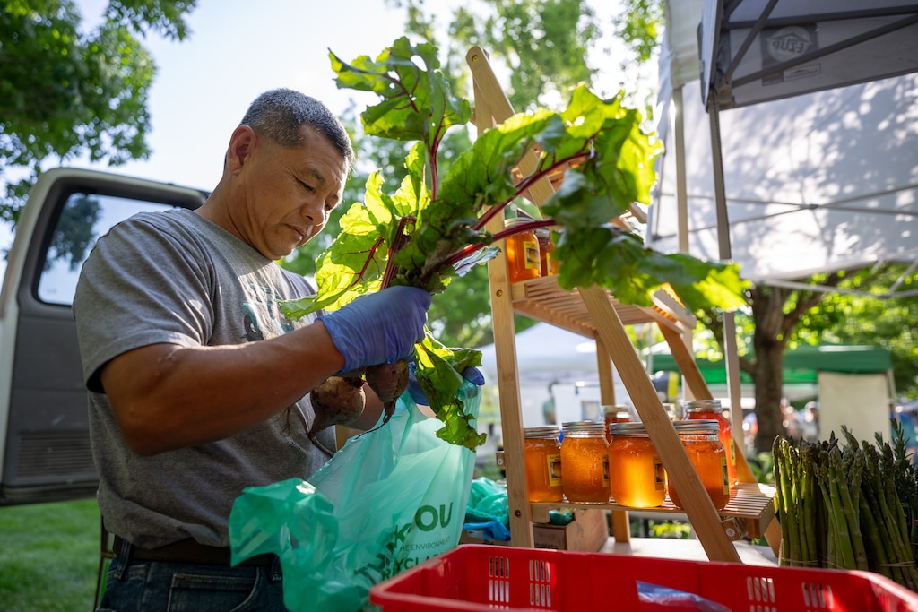 (Trent Nelson  |  The Salt Lake Tribune) David Chen bags produce at Zoe's Natural Garden booth during the Downtown Farmers Market in Salt Lake City on Saturday, June 6, 2026.