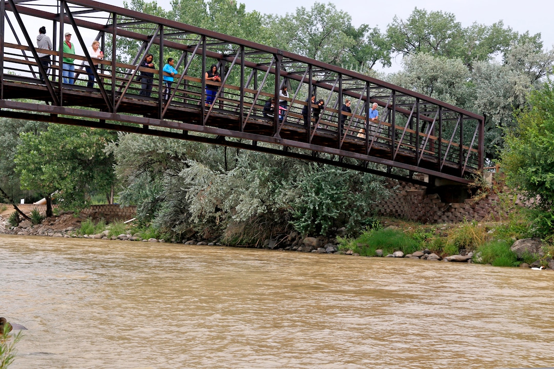 Onlookers view the Animas River from a bridge as orange sludge from a mine spill upstream flows past Berg Park in Farmington, N.M., Saturday, Aug. 8, 2015. About 1 million gallons of wastewater from Colorado's Gold King Mine began spilling into the Animas River on Wednesday when a cleanup crew supervised by the Environmental Protection Agency accidentally breached a debris dam that had formed inside the mine. The mine has been inactive since 1923. (Alexa Rogals/The Daily Times via AP)