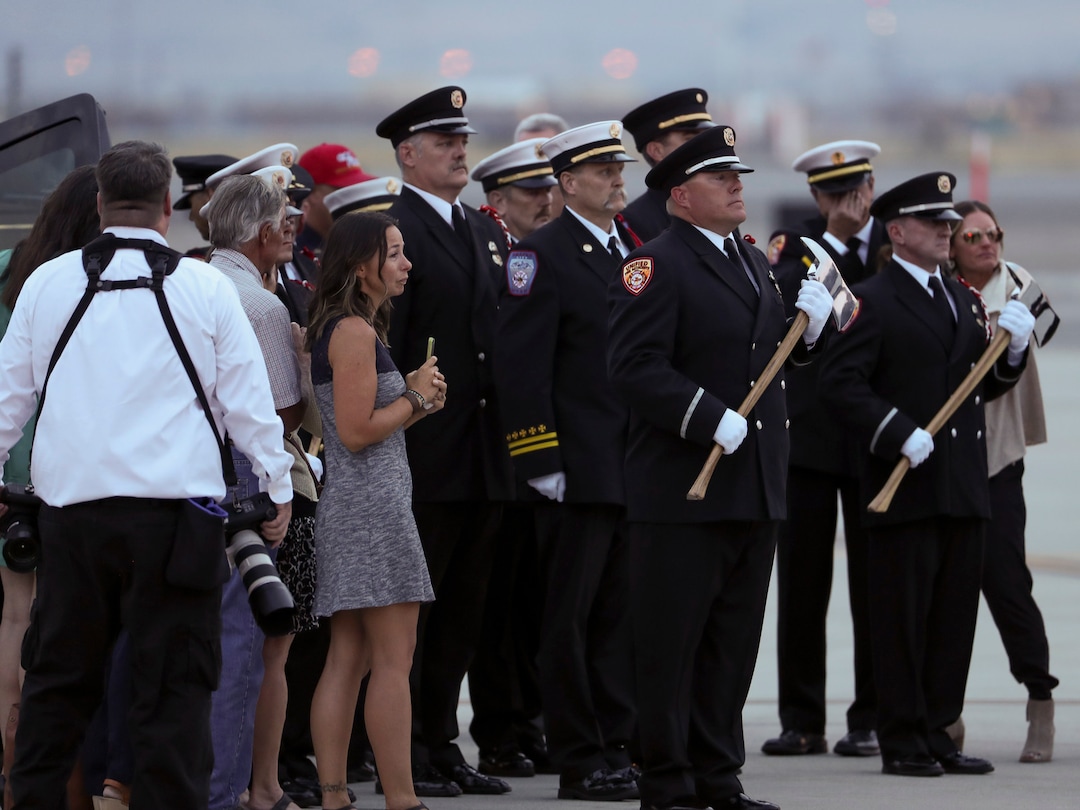 (Steve Griffin  |  Deseret News, pool photo)  Members of the Draper City Fire Department and Unified Fire Authority Honor Guard stand with family members after the casket of Draper Battalion Chief Matt Burchett is placed in a hearse after being transported from California to Utah in a C130-J by the California Air National Guard. The C130-J landed at the Utah Air National Guard Base in Salt Lake City on Wednesday, Aug. 15, 2018. Burchett was killed while fighting the Mendocino Complex Fire north of San Francisco.