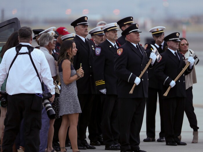 (Steve Griffin  |  Deseret News, pool photo)  Members of the Draper City Fire Department and Unified Fire Authority Honor Guard stand with family members after the casket of Draper Battalion Chief Matt Burchett is placed in a hearse after being transported from California to Utah in a C130-J by the California Air National Guard. The C130-J landed at the Utah Air National Guard Base in Salt Lake City on Wednesday, Aug. 15, 2018. Burchett was killed while fighting the Mendocino Complex Fire north of San Francisco.