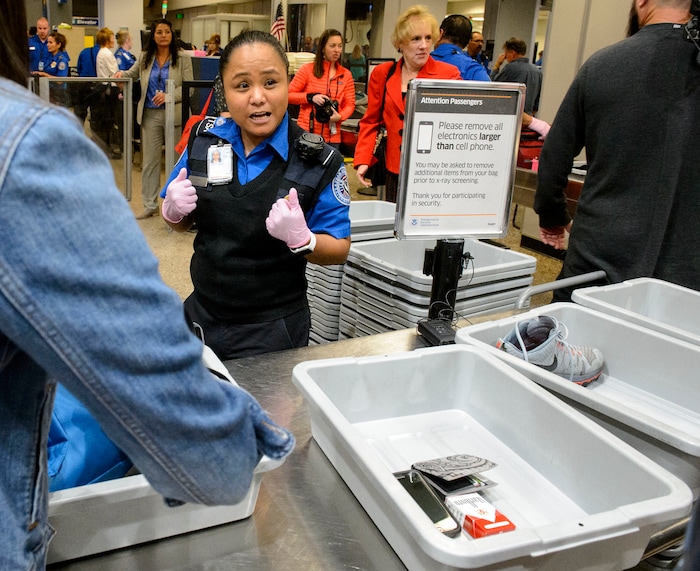 (Steve Griffin  |  The Salt Lake Tribune)  TSA agent Joyce Domingo helps airline passengers as they go through security at Salt Lake International Airport Thursday October 5, 2017. TSA has implemented stronger carry-on baggage screening for electronic devices where any electronic device larger than a cell phone needs to be in bins for X-ray.