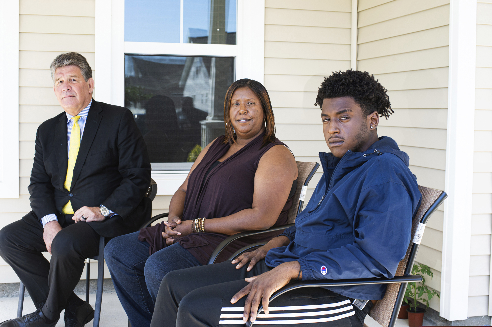 (Mark Darrough | Port City Daily | AP) In this May 7 photo, provided by the Port City Daily, high school senior Dameon Shepard, right, his mother, Monica Shepard, and their attorney Jim Lea, left, pose for a photo at the Shepard's home in the Rocky Point area of Pender County, in North Carolina. New Hanover County Sheriff's Deputy Jordan Kita faces criminal charges after authorities say he led a group of people to the wrong location, the Shepards' home, in a search for a missing girl. Kita has also been fired.