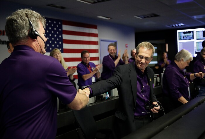 Project manager Earl Maize, center, shakes hands with Bill Heventhal in mission control at NASA's Jet Propulsion Laboratory, Friday, Sept. 15, 2017, in Pasadena, Calif. after confirmation of Cassini's demise. Cassini disintegrated in the skies above Saturn early Friday, following a remarkable journey of 20 years. (AP Photo/Jae C. Hong, Pool)