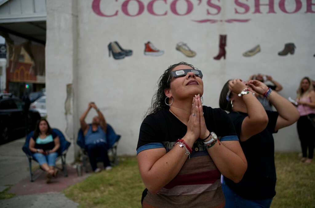 (Todd Heisler | The New York Times) Mireya Munoz of Eagle Pass prays at the end of the total eclipse while viewing the solar eclipse in Eagle Pass, Texas, Monday, April 8, 2024.