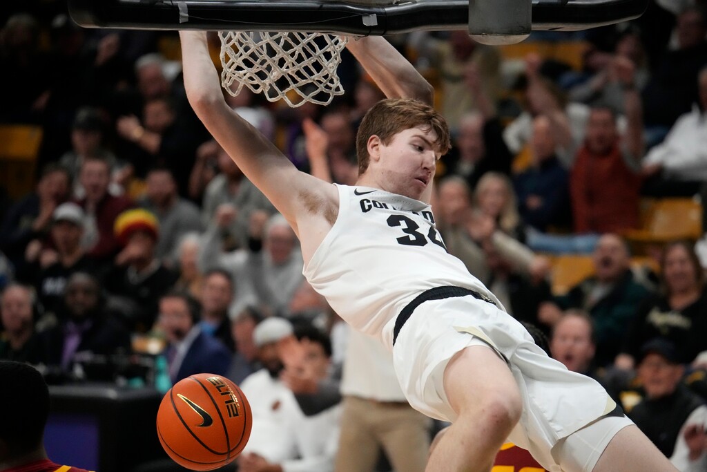 Colorado center Lawson Lovering hangs on the rim after dunking the ball for a basket against Southern California in the second half of an NCAA college basketball game Thursday, Feb. 23, 2023, in Boulder, Colo. (AP Photo/David Zalubowski)