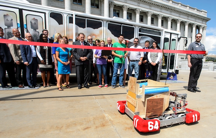 (Steve Griffin | The Salt Lake Tribune) Jordan High School's FIRST Robotics Team members Nicole Brooks and Ethan Nielsen, center right, maneuver their Beet Bot into position so Gov. Gary Herbert can control it to cut the red ribbon during ceremony by the Utah STEM Action Center to celebrate the launch of the Utah STEM Bus into the 2016-2017 school year. The Center transformed a donated Utah Transit Authority bus into a mobile classroom to bring hands-on science, technology, engineering and math experiences to Utah students.