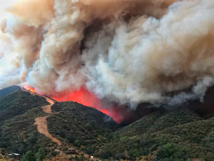 (Mike Eliason | Santa Barbara County Fire Department via AP) In this photo provided by the Santa Barbara County Fire Department, flames advance towards a large fire break near homes along Gibraltar Road north of Santa Barbara, Calif., Saturday, Dec. 16, 2017.