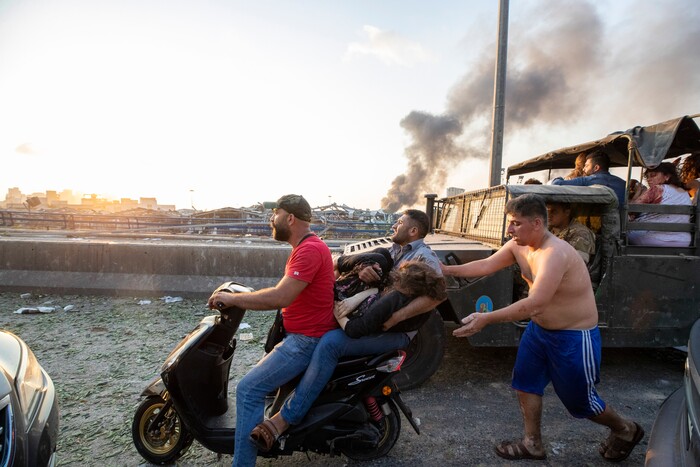 People evacuate wounded after of a massive explosion in Beirut, Lebanon, Tuesday, Aug. 4, 2020. Massive explosions rocked downtown Beirut on Tuesday, flattening much of the port, damaging buildings and blowing out windows and doors as a giant mushroom cloud rose above the capital. Witnesses saw many people injured by flying glass and debris. (AP Photo/Hassan Ammar)