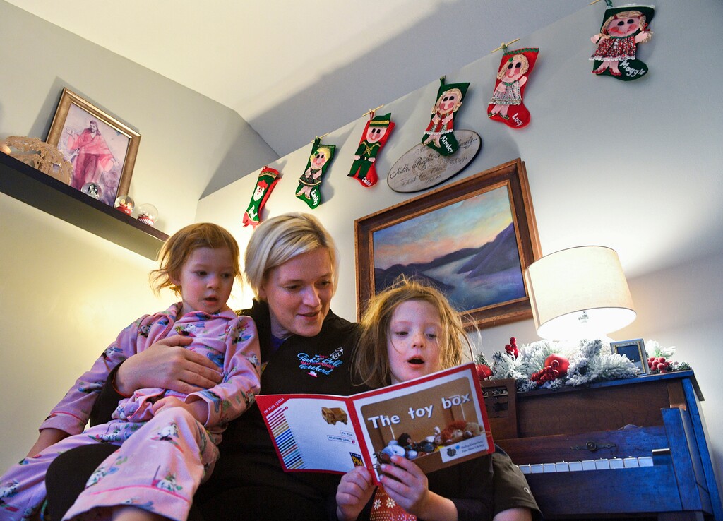 (Isaac Hale photo for The Washington Post) Becca Riding helps read a short story to her daughters Maggie, 3, left, and Lucy, 5, before school at their home in American Fork, Utah.