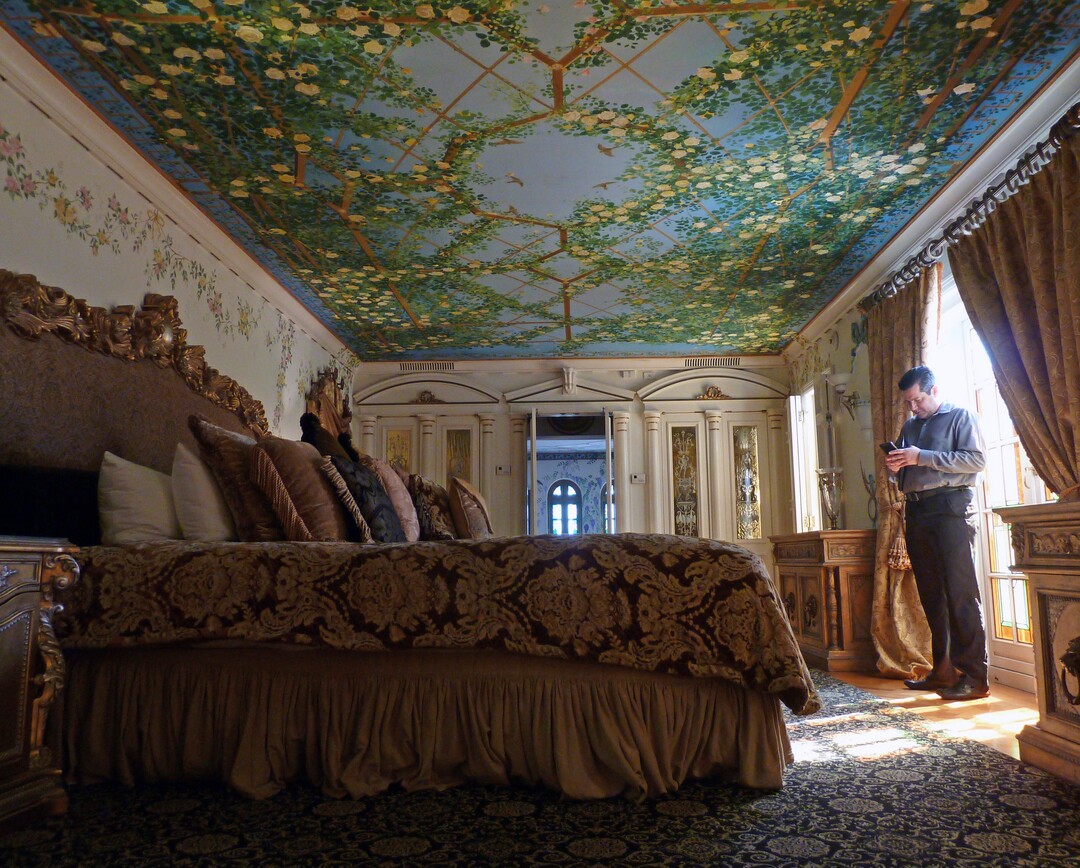 In this Tuesday, Dec. 26, 2017 photo, Reynaldo Ramirez, Victor Hotels director of sales, stands in the Venus Suite at The Villa Casa Casuarina in Miami Beach, Fla. The suite is one of 10 suites featuring frescos and other opulent artwork created by fashion designer Gianni Versace, who once used the property as a private home. (AP Photo/Jennifer Kay)