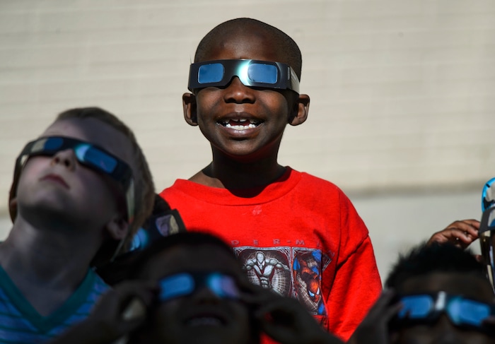 (Steve Griffin  |  The Salt Lake Tribune) Meadowlark Elementary School first-grader Ali Eftin smiles as he watches The Great Eclipse during the Salt Lake School District's first day of the 2017-2018 school year. STEAM teacher-coordinator Wendi Laurence who formerly worked at NASA has been planning an event around the eclipse. All students had glasses to view the event and many had lunch outside at the Salt Lake City school Monday August 21, 2017.