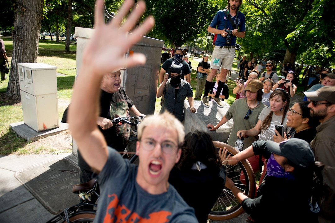 (Jeremy Harmon |  The Salt Lake Tribune) A man tries to prevent a Tribune photographer from photographing a fight that broke out between protesters and a man yelling racist taunts following an inland port protest on Tuesday, July 9, 2019.