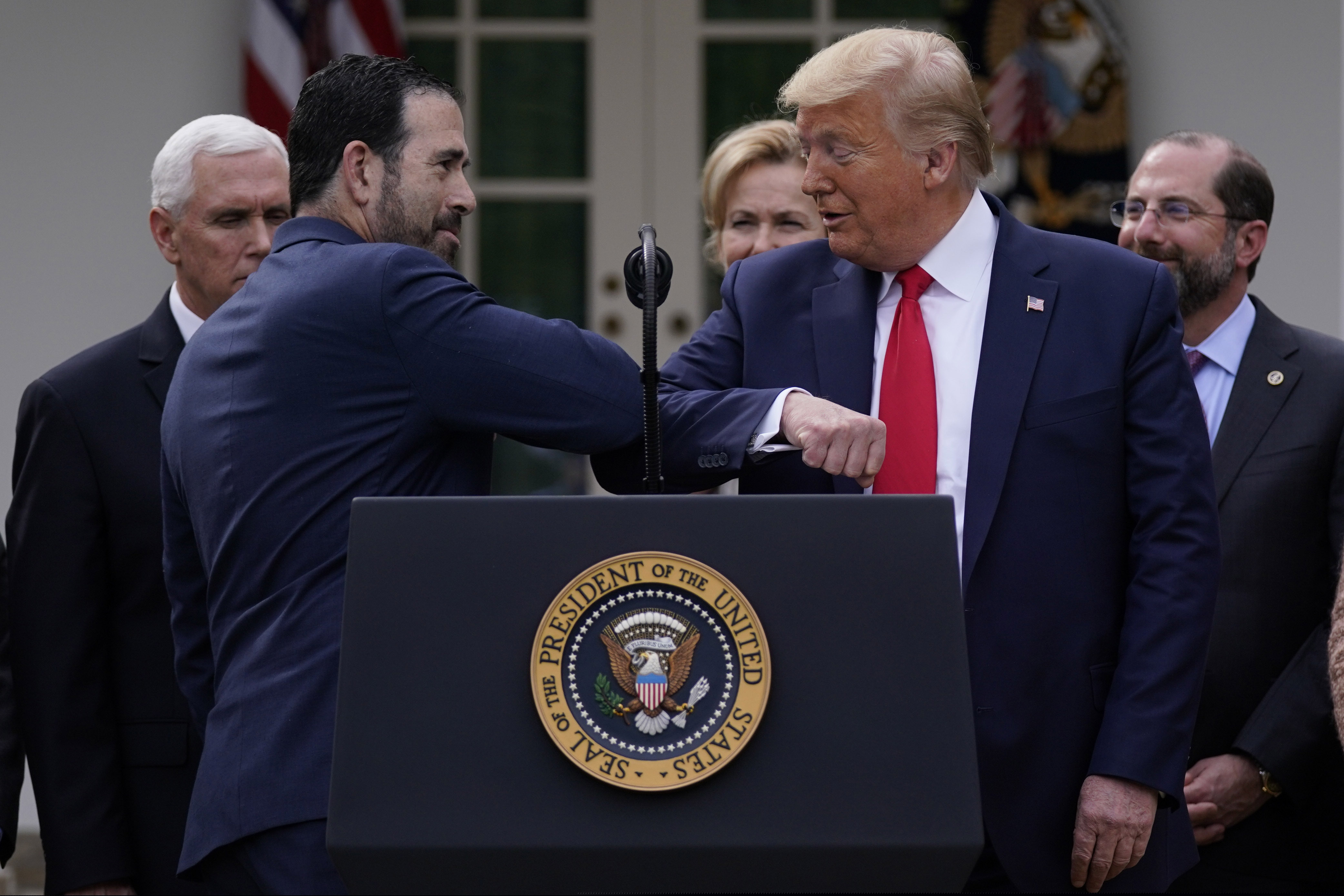 (Evan Vucci | AP) LHC Group’s Bruce Greenstein elbow bumps with President Donald Trump during a news conference about the coronavirus in the Rose Garden at the White House, Friday, March 13, 2020, in Washington.