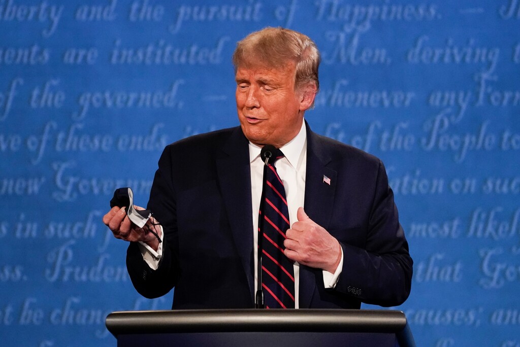 (Julio Cortez | AP file photo)
President Donald Trump holds out his face mask during the first presidential debate Tuesday at Case Western University and Cleveland Clinic, in Cleveland, Ohio. President Donald Trump and first lady Melania Trump have tested positive for the coronavirus, the president tweeted early Friday.