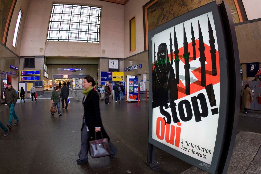 (Salvatore Di Nolfi/Keystone via AP file) A poster from the right-wing Swiss People's Party (SVP/UDC) in November 2009 depicts a woman wearing a burqa in front of a Swiss flag upon which are minarets which resemble missiles, at the central station in Geneva, Switzerland. Later in the month, a successful referendum banned the construction of new minarets in the country.