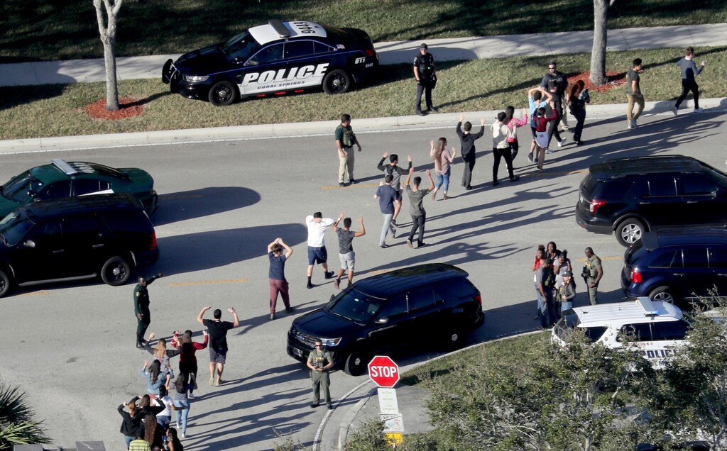 (Mike Stocker/South Florida Sun-Sentinel via AP, File) In this Feb. 14, 2018 file photo, students hold their hands in the air as they are evacuated by police from Marjory Stoneman Douglas High School in Parkland, Fla., after a shooter opened fire on the campus.