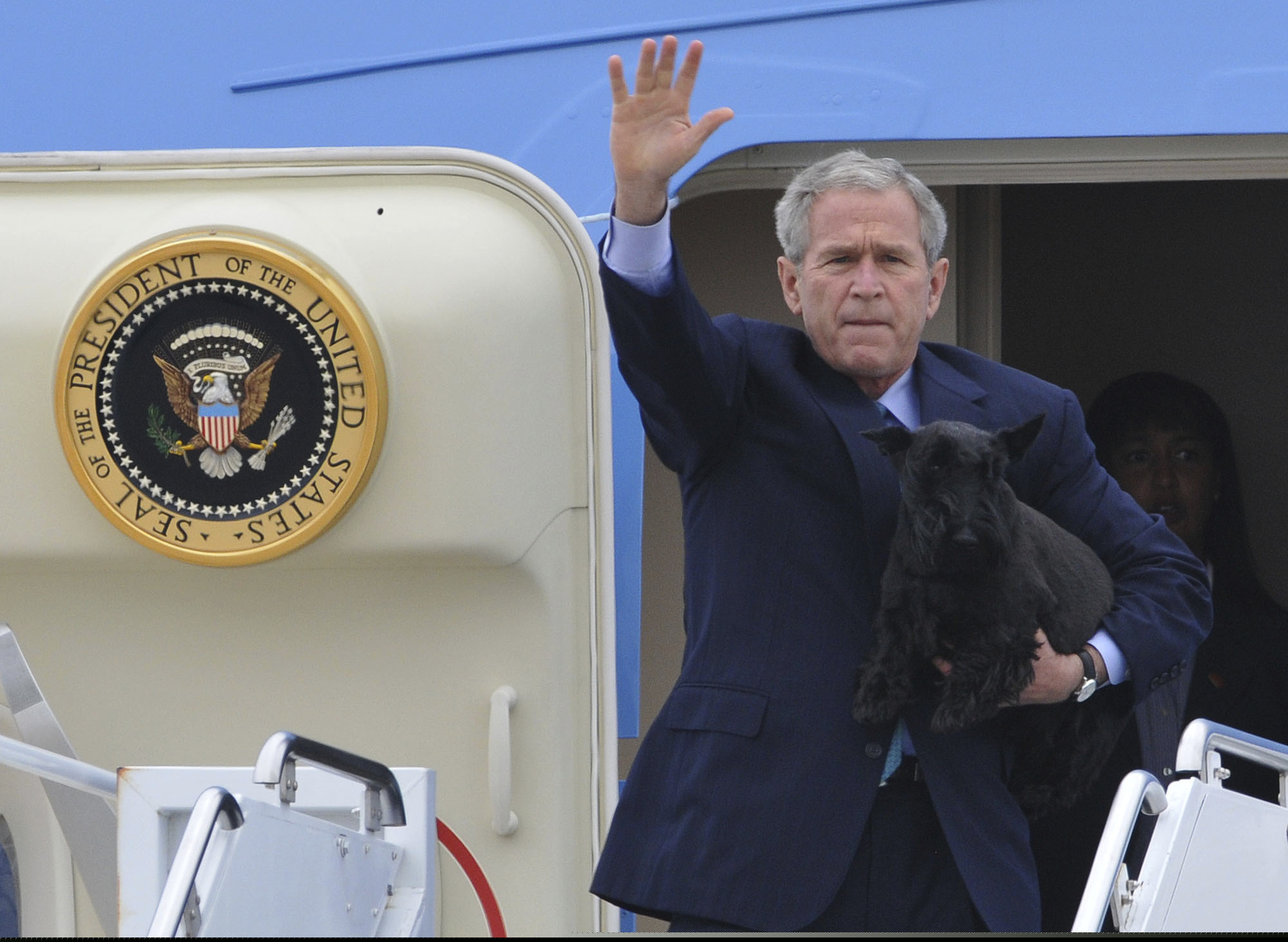 FILE - In this Aug. 15, 2008, file photo, President George W. Bush, carrying his dog Barney, waves as he arrives at TSTC airfield in Waco, Texas, to begin his summer vacation at his ranch near Crawford Texas. President Donald Trump isn't hiding the fact that he isn't a dog person. While he appeared impressed when describing the drug-detecting abilities of German shepherds that work for the U.S. Secret Service, he made it clear that he can get by in his daily life without the slobbery canine companionship welcomed by many of his predecessors.(AP Photo/Rod Aydelotte, File)