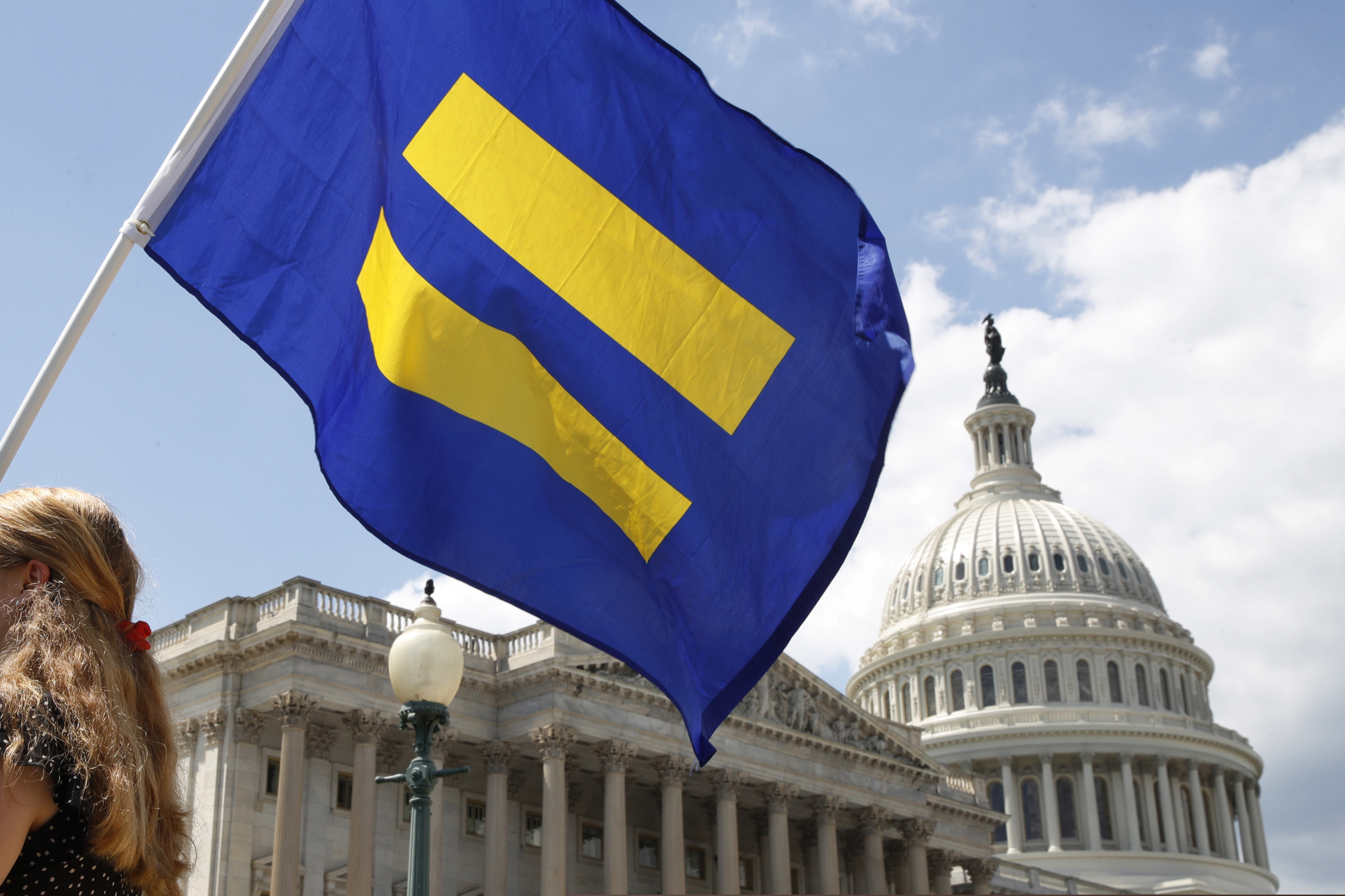 (Jacquelyn Martin | The Associated Press) In this July 26, 2017, file photo, a supporter of LGBT rights holds up an "equality flag" on Capitol Hill in Washington, during an event held by Rep. Joe Kennedy, D-Mass. in support of transgender members of the military. The Trump administration is asking the Supreme Court to fast-track cases on the president's decision to prevent certain transgender people from serving in the military. The administration asked the court on Nov. 23, 2018, to take up three cases on the issue.