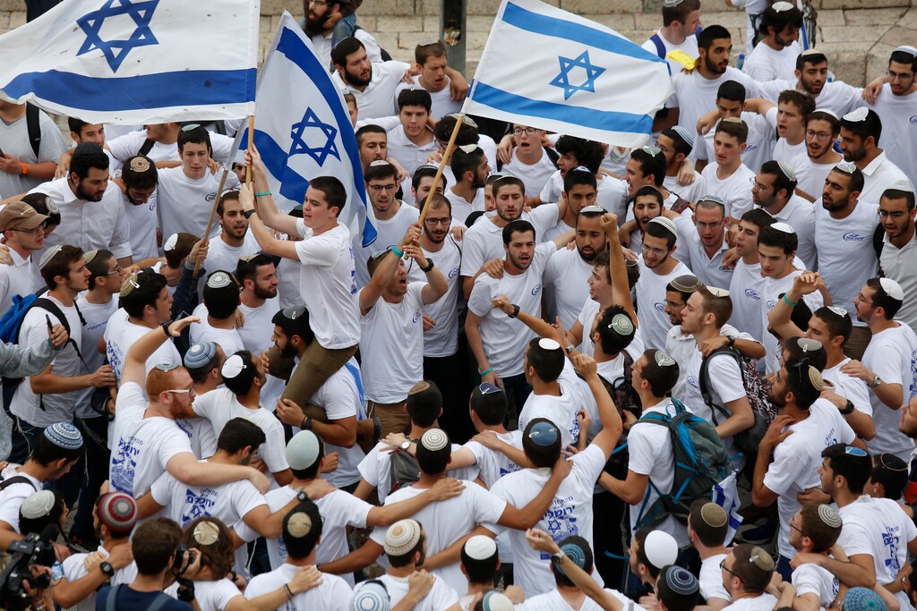Israeli youths wave national flags outside the Old City's Damascus Gate, in Jerusalem, Sunday, May 13, 2018. Israel is marking the 51st anniversary of its capture of east Jerusalem in the 1967 Middle East war. (AP Photo/Ariel Schalit)