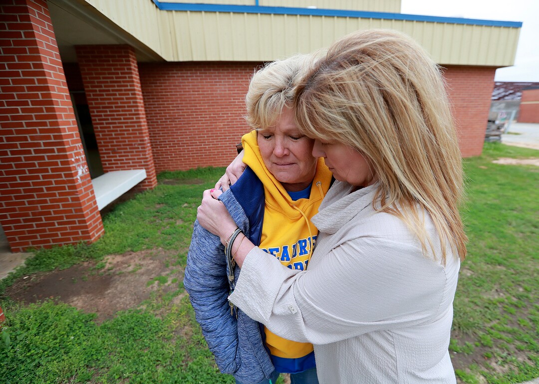 Beauregard High School teachers Julie Howard, left, and Michelle Johnson console each other outside the school gymnasium as they prepare to attend a prayer circle at the school for those in their community that lost their lives in a Sunday night tornado on Monday, March 4, 2019, in Beauregard, Ala. (Curtis Compton/Atlanta Journal-Constitution via AP)