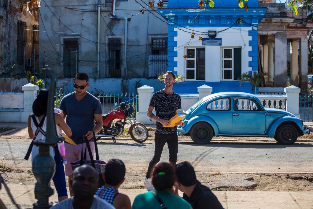 Enmanuel Carrasco, center, smiles holding his newly issued U.S. visa as he leaves the U.S. embassy in Havana, Cuba, Monday, Oct. 2, 2017. Thousands of Cubans have had their travel plans thrown into limbo by the U.S. government's announcement it has suspended visa processing in Havana. Carrasco's visa had been approved prior to the announcement. (AP Photo/Desmond Boylan)