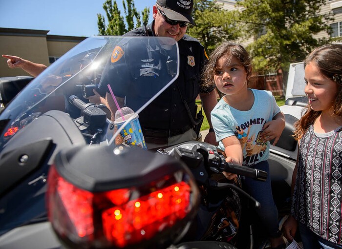 (Trent Nelson | The Salt Lake Tribune)Catalina and Faith Cardenes take a turn on Salt Lake City police officer Michael Blackburn's bike Wednesday June 13, 2018, during an event at a Salt Lake City 7-Eleven store  promoting the donation of 7,500 Slurpee coupons by the company for police officers to hand out to children.
