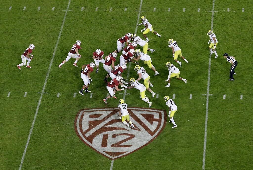 (Jeff Chiu | AP) Stanford quarterback Kevin Hogan (8) drops back against Oregon over Pac-12 logo at Stanford Stadium during the fourth quarter of an NCAA college football game in Stanford, Calif., Thursday, Nov. 7, 2013. Stanford won 26-20. With the defection of its most storied programs, the future of the Pac-12 looks dire.