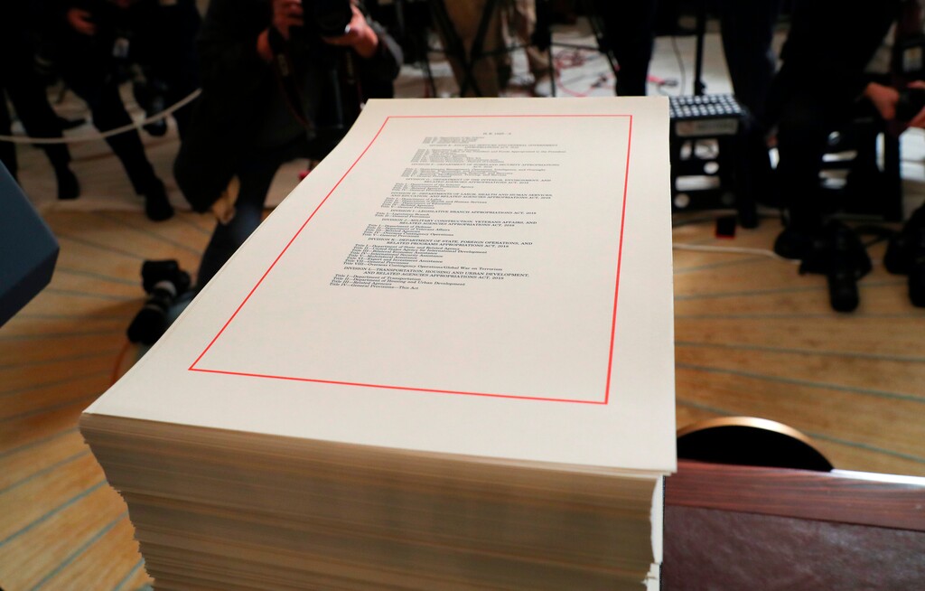 FILE - In this March 23, 2018, file photo, a copy of the $1.3 trillion spending bill is stacked on a table in the Diplomatic Room of the White House in Washington. A new analysis says President Donald Trump's tax cuts and last month's big spending bill will send the federal deficit toward $1 trillion. The Congressional Budget Office says tax and spending bills will push the deficit to $804 billion this year and nearly $1 trillion for 2019.  (AP Photo/Pablo Martinez Monsivais)