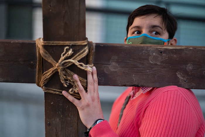 (Francisco Kjolseth | The Salt Lake Tribune) Allison Dupler takes a turn carrying the cross as mask wearing Utah Christians walk the streets of Salt Lake City beginning at Cathedral of the Madeleine on Good Friday, to symbolically mark Jesus' carrying the cross to his crucifixion, April 2, 2021.