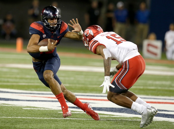 Arizona quarterback Brandon Dawkins (13) stiff arms Utah defensive back Corrion Ballard in the second half during an NCAA college football game, Friday, Sept. 22, 2017, in Tucson, Ariz. Utah defeated Arizona 30-24. (AP Photo/Rick Scuteri)