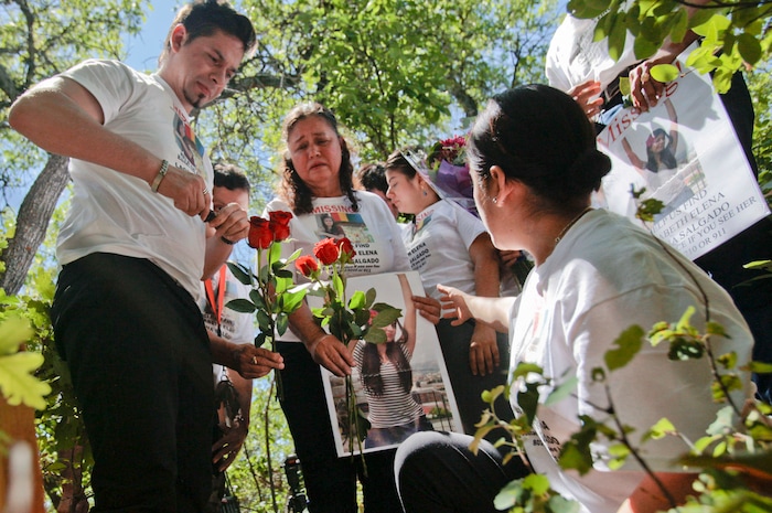 Julio Cesar Laguna-Salgado, left, along with family members, lay flowers next to a cross, Friday, June 15, 2018, in Hobble Creek Canyon near Provo, Utah, where his sister Elizabeth Elena Laguna-Salgado was found. The remains of the 26-year-old Mexican woman were discovered by a passer-by looking for a camping spot last month. She had been missing since April 16, 2015, when she was last seen walking home from her English language class. (Evan Cobb/The Daily Herald via AP)