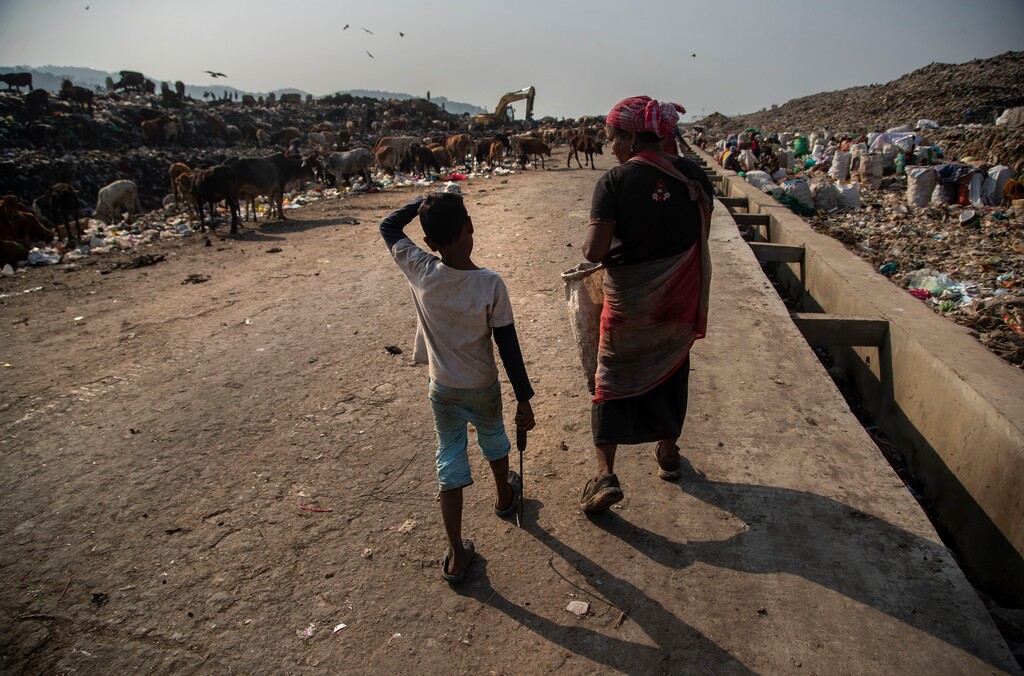 Imradul Ali, 10, left, and his mother Anuwara Beghum, 30, arrive to look for recyclable material at a landfill on the outskirts of Gauhati, India, Thursday, Feb. 4, 2021.  (AP Photo/Anupam Nath)