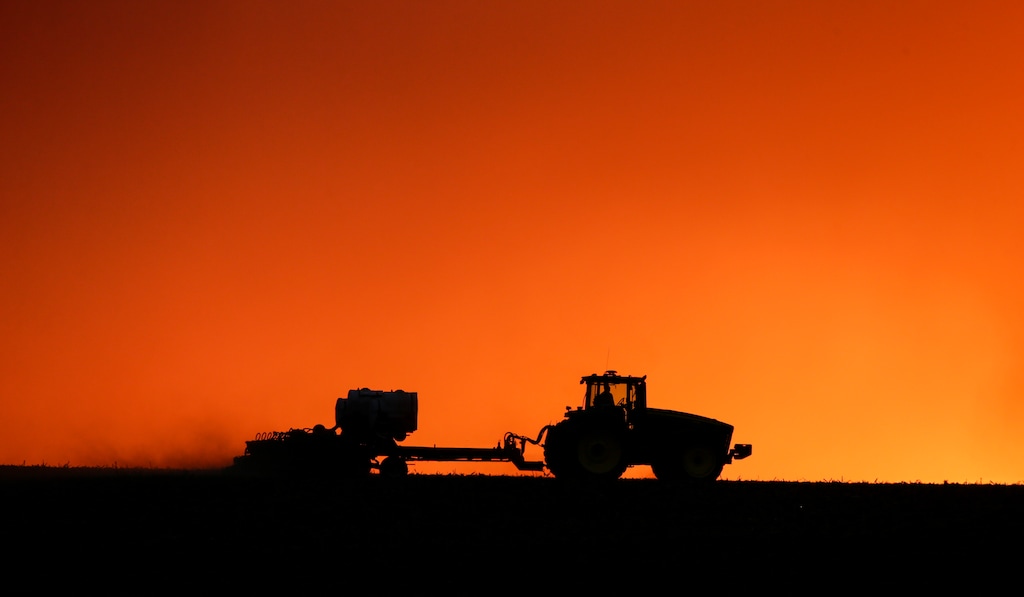 (Jim Slosiarek | AP) A farmer is silhouetted against the setting sun in 2020 near Walford, Iowa. The Church of Jesus Christ of Latter-day Saints owns tens of thousands of cropland acres in the state.
