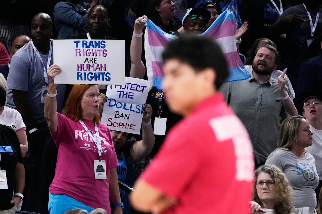 (Nam Y. Huh | AP) Fans stand up as they hold signs while Chicago Sky guard Natasha Cloud argues with former NBA center Enes Kanter Freedom during the second half of a WNBA basketball game against the Indiana Fever, Sunday, Aug. 23, 2026, in Chicago.