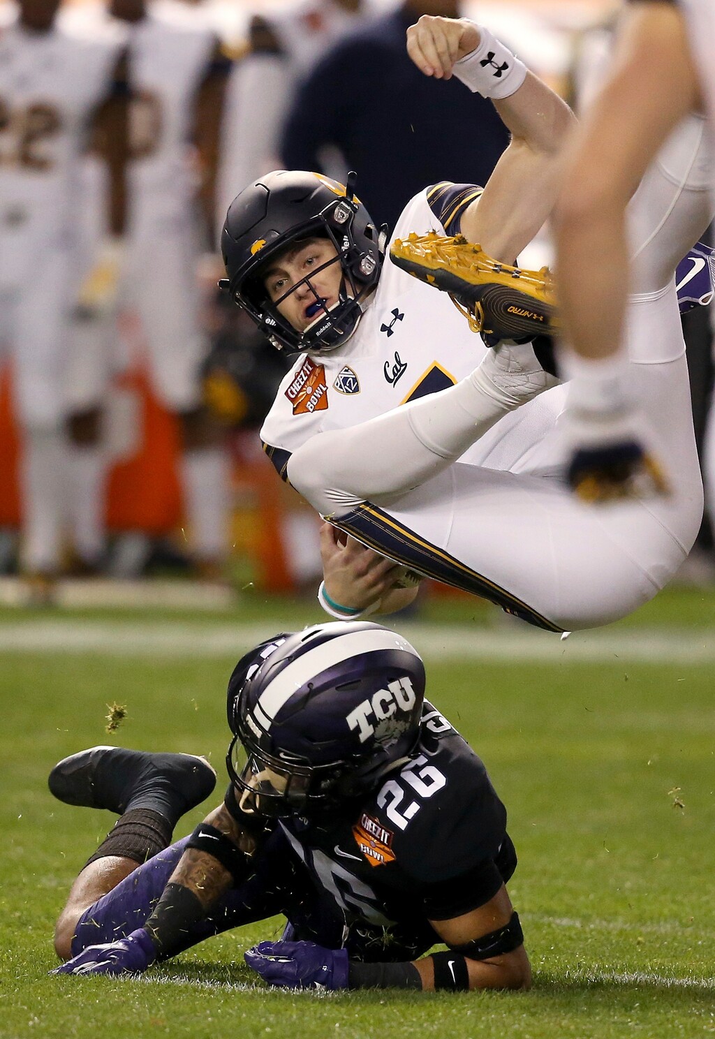 California quarterback Chase Garbers, top, gets upended by TCU safety Vernon Scott (26) during the first half of the Cheez-It Bowl NCAA college football game Wednesday, Dec. 26, 2018, in Phoenix. (AP Photo/Ross D. Franklin)